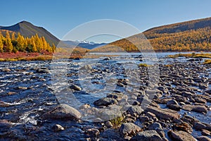 Beautiful autumn morning. Mountain stone stream surrounded by hills