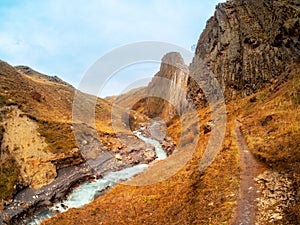 Beautiful autumn mountain landscape with bent mountain river. Bright alpine scenery with mountain river in red colors in fall time