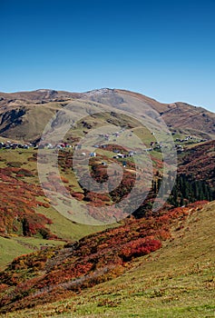 Beautiful autumn mountain landscape with colorful trees, snow peaks and old houses. Traveling through the mountains of Georgia