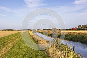 Beautiful autumn nature landscape view.  Small river along field merging to blue sky.