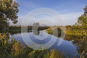Beautiful autumn nature landscape view.  Small river along field merging to blue sky.