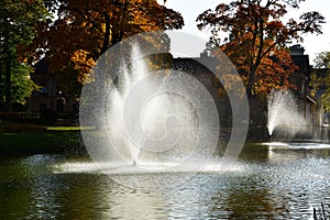 Beautiful autumn park with colorful foliage and splashing water fountain