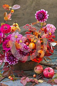 Beautiful autumn pink red orange bouquet with dahlia, fall flowers, colorful leaves and apples