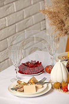 Beautiful autumn place setting and decor for festive dinner on table indoors