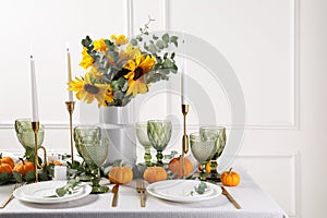Beautiful autumn table setting with bouquet indoors. Plates, cutlery, glasses and floral decor