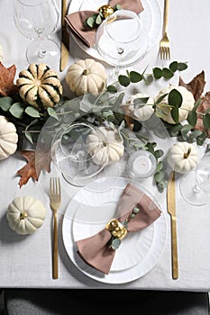 Beautiful autumn table setting. Plates, cutlery, glasses, pumpkins and floral decor, flat lay