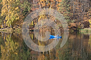 Forest reflected in a lake in Autumn with boat