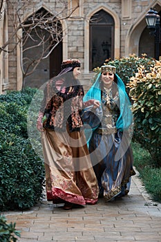 Beautiful azeri women in traditional Azerbaijani dress running by the wooden door