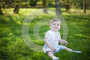 Beautiful baby boy on green grass in summer