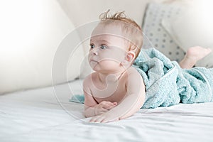 Portrait of beautiful baby boy after having bath lying on bed in bedroom