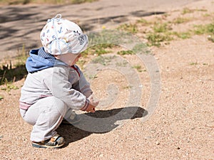 Beautiful baby boy playing on the playground with her mother. The is dressed in a light bike