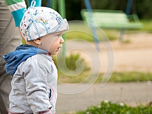 Beautiful baby boy playing on the playground with her mother. The is dressed in a light bike