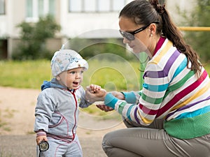 Beautiful baby boy playing on the playground with her mother. The is dressed in a light bike