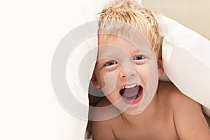 Beautiful baby boy under white blanket. Copy space