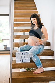 Beautiful baby future mother smoothing tummy and smiling in new home