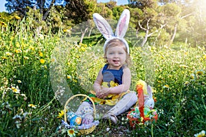 A beautiful baby girl with bunny ears on a easter egg hunt in the garden