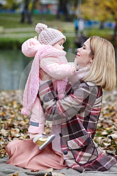 Beautiful baby girl with mother sitting on the plaid. Family outdoor