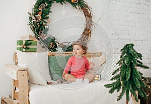 Beautiful baby girl near a Christmas tree with gifts with