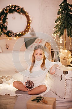 Beautiful baby girl near a Christmas tree with gifts