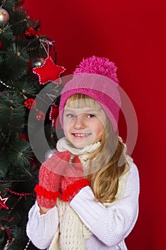 Beautiful baby girl in a pink hat and gloves in New Year's Eve smiling and looking for a gift