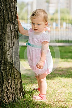 Beautiful baby girl touching a tree