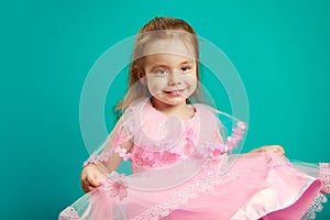 Beautiful baby girl wears pink dress on blue isolated