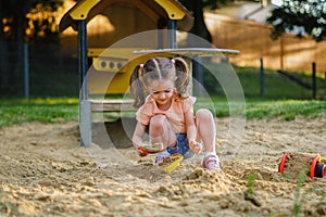 Beautiful baby  having fun on sunny warm summer day - Cute toddler girl playing in sand on outdoor playground