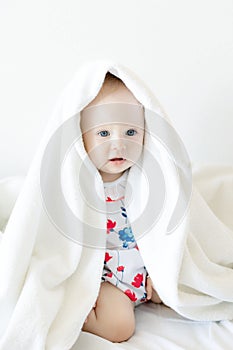 Beautiful baby kid Peeps out from under the sheets and fervently plays posing for the camera