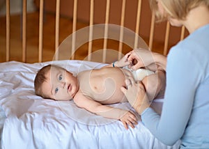 Beautiful baby looking at camera while mother changing nappy