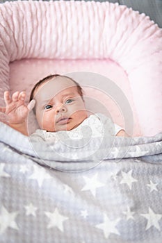 Beautiful baby looking at camera waving with her hand covered by a blanket of stars