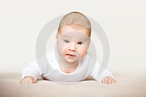 Beautiful baby lying on his stomach in bed.