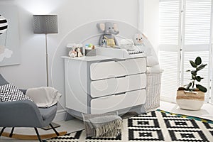 Beautiful baby room interior with modern changing table and rocking chair