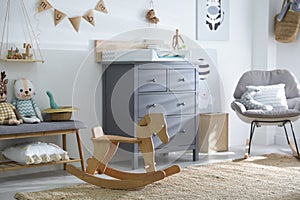 Beautiful baby room interior with toys, rocking chair and modern changing table