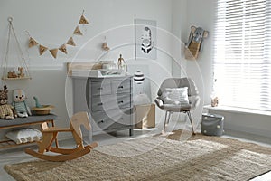 Beautiful baby room interior with toys, rocking chair and modern table