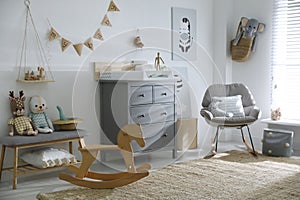 Beautiful baby room with toys, rocking chair and modern changing table