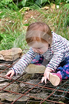 Beautiful baby sitting, smiling and posing, portrait. Little cute girl is playful in garden. Child is playing outside in park.