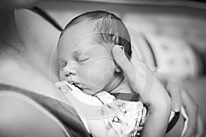 Beautiful baby sleeping in selective foxus, black and white. Close up portrait of newborn sleeping in mother`s hands