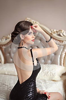 Beautiful back of elegant woman in black dress posing on mo