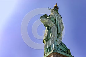 Beautiful back photo of the Statue of Liberty holding her torch on a sunny day in Manhattan, known as the lady of New York City
