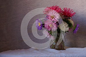 Beautiful background with bouquet of colorful asters in a vase Callistephus chinensis