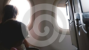 Beautiful background shot of happy little girl and boy enjoying view from airplane window seat during vacation trip.