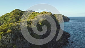 Beautiful background with tropical island in ocean, green mountains and cliff, aerial view.