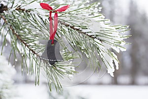 Beautiful background  with Unique handmade black ceramic Christmas decoration shape of bell on pine tree.