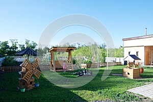 Beautiful backyard of a country house. Happy lifestyle concept. There are swing, sandpit for children, flowers, scenery, mill