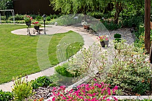 Beautiful backyard landscape design. View of colorful trees and decorative trimmed bushes and rocks.Path in the garden