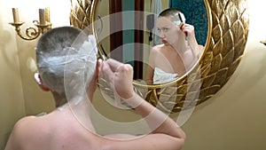 Beautiful bald woman looks in a luxurious bathroom mirror and does her hair, shaves her hair with a dangerous razor