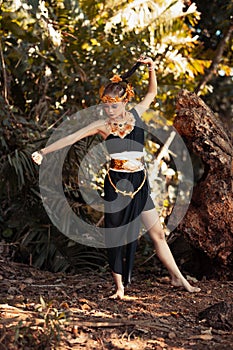 Krásný žena držení její černý vlasy zatímco pózování v černý tanec šaty uvnitř džungle 