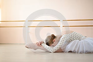 Beautiful ballerina in body and white tutu is training in a dance class. Young flexible dancer posing in pointe shoes