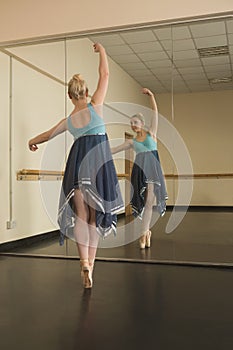 Beautiful ballerina dancing in front of mirror