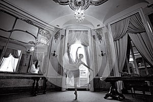 Beautiful ballerina dancing in a luxurious hall with a chandelier and mirrors